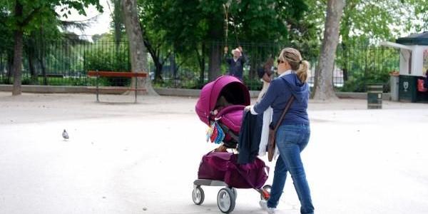 Una madre pasea a su bebé por el parque 