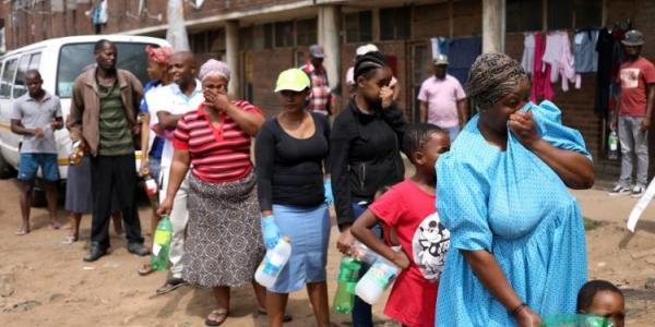 Personas en África hacen una cola con las mascarillas en sus rostros 