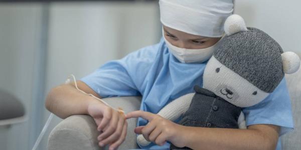 Niño con cáncer infantil en el hospital abrazando un peluche
