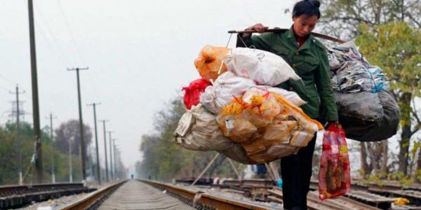 Un trabajador migrante chino transporta basura por las vías del ferrocarril en diciembre de 2004 en Wuhan, China. // GETTY