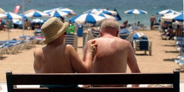Dos personas mayores en la playa utilizando protección solar