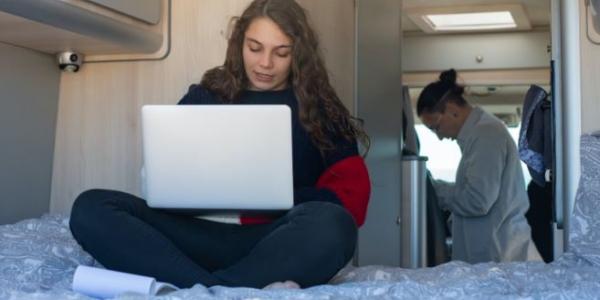 Chica sentada en un colchón de una autocaravana 