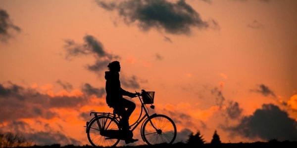 Una persona paseando en bicicleta al atardecer