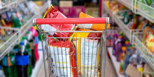 Un carrito de la compra lleno de bolsas de snacks por el pasillo de un supermercado