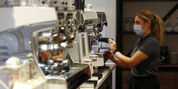 Una camarera sirve café en un bar de Granada. La hostelería es uno de los sectores que más abusa de la temporalidad.