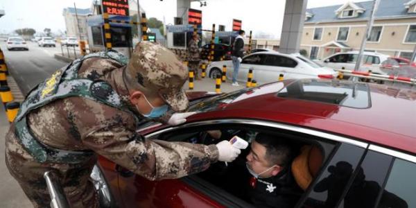 Un militar comprueba la temperatura de un conductor en uno de los accesos por carretera a Wuhan, China, como medida contra la propagación del brote del coronavirus surgido en la región. Foto de Yuan Zheng de EFE