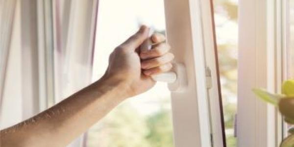 Una mano abre una ventana para ventilar la sala 