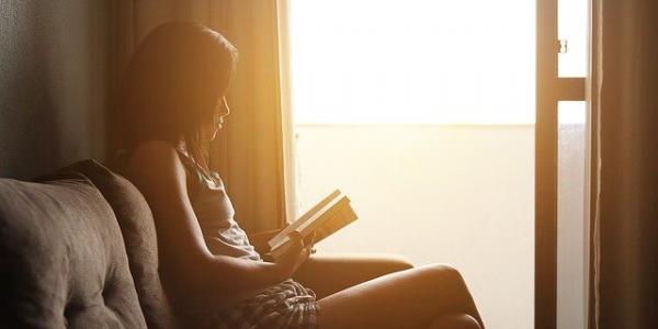 Chica leyendo un libro junto a la ventana