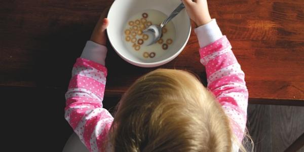 Niña desayuna plato de cereales