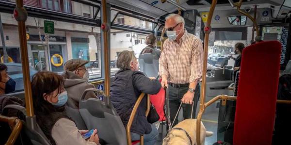Persona con discapacidad visual y su perro guía en un autobús