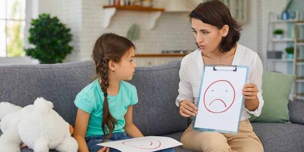 Mujer explicando los sentimientos a una niña con Asperger / Adobe Stock