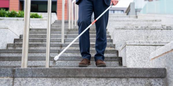 Una persona con discapacidad visual usando bastón de ciego para las escaleras