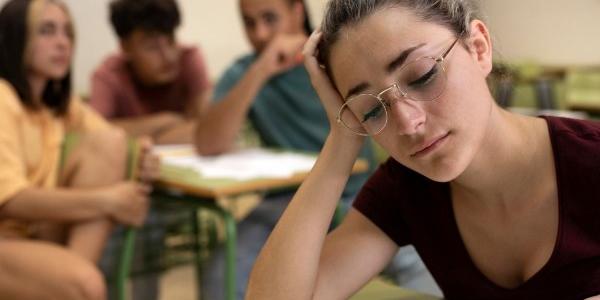 Una estudiante en primer plano, observada por otros que se encuentran detrás