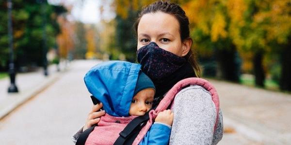 Mujer con mascarilla paseando con un bebé al aire libre