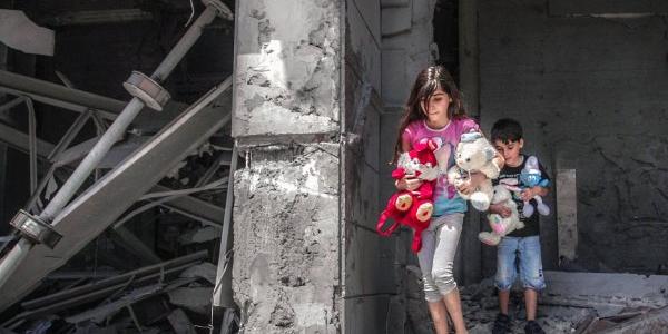 Niños palestinos recogiendo sus juguetes de su hogar destrozado en Gaza