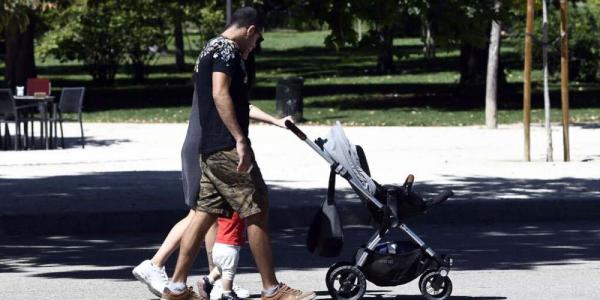 Una pareja empujan el carrito de bebé en un parque de Madrid.