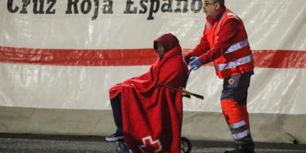 Un voluntario de Cruz Roja ayuda a uno de los inmigrantes llegados al puerto de Arguineguín (Mogán), tras ser rescatados de una patera al sur de Gran Canaria.