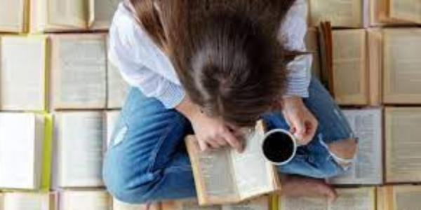 Una joven lee mientras se toma un café