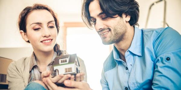 Pareja de jóvenes con una casa en miniatura 