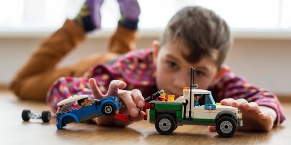 Un niño jugando en el suelo con un coche de juguete 