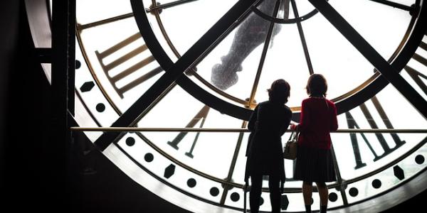 Dos mujeres de espaldas frente a un reloj