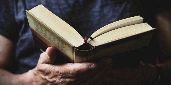 Un hombre sujeta un libro abierto para leer