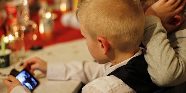 Dos niños utilizando un móvil durante una cena familiar navideña