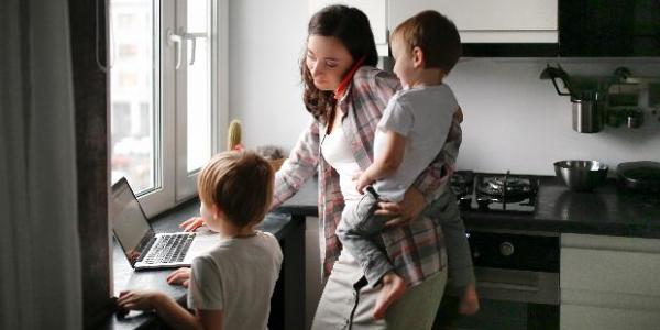Madre cuidando de sus hijos mientras trabaja en casa