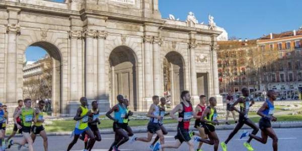 Varios corredores atraviesan la Puerta de Alcalá durante la maratón de Madrid