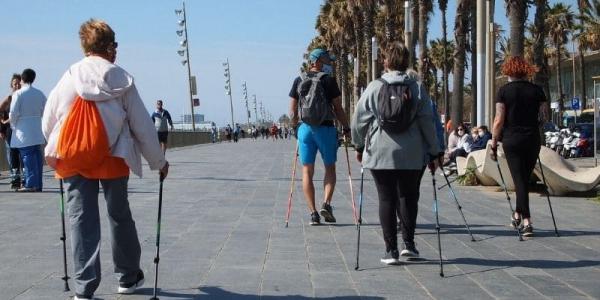 Varias personas de marcha nórdica por un paseo marítimo