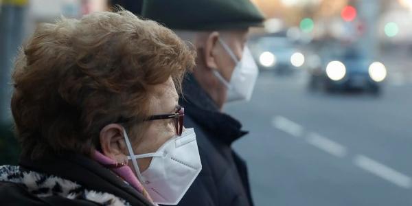 Una pareja de ancianos con mascarillas esperando para cruzar una calle en Madrid 