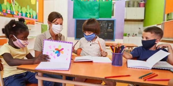 Profesora y varios niños con mascarillas en el colegio