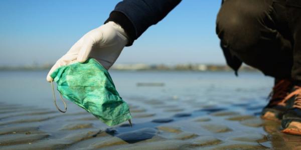 Persona recogiendo una mascarilla del mar / Imagen: iStock