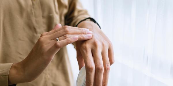 Manos de una mujer aplicándose crema