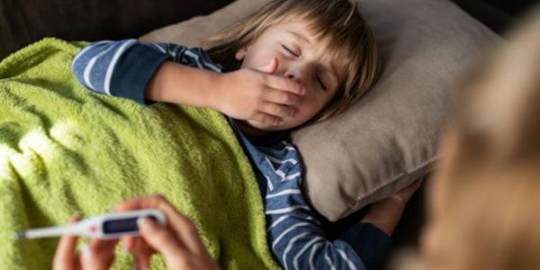 Un niño guarda reposo en la cama y se lleva la mano a la boca, en un golpe de tos 