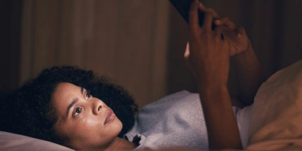 Mujer con insomnio causado por mirar el móvil