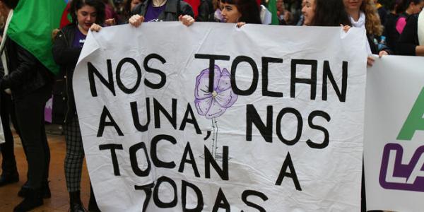 Jóvenes onubenses tras una pancarta de la manifestación del 25-N de 2018. / JOSUÉ CORREA (Huelva)