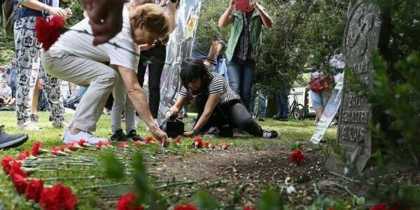 Personas depositan claveles junto al monolito en recuerdo a Gladys del Estal.