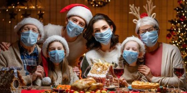 Foto de familia donde todos usan mascarilla rodeados de preciosos adornos navideños 