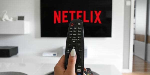 Persona con un mando apuntado a su tele viendo Netflix