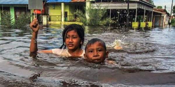 Unos niños caminan entre las aguas de las inundaciones en Palangka Raya, en Kalimantan Central (Indonesia).