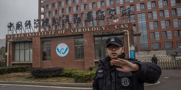 Un miembro del equipo de seguridad intenta evitar que se tomen fotografías del Instituto de Virología de Wuhan, en China / EFE