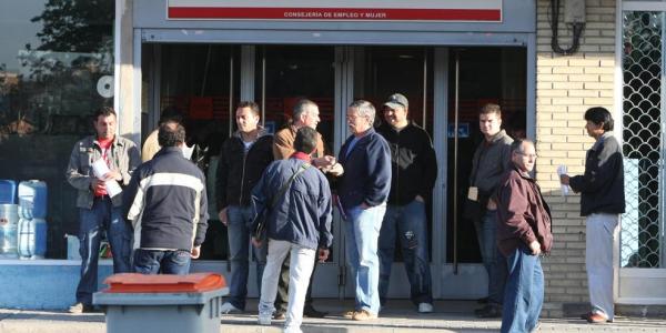 Cola de personas esperando a las puertas de una oficina de empleo.