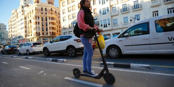 Una persona transita por la calle con un patinete eléctrico 