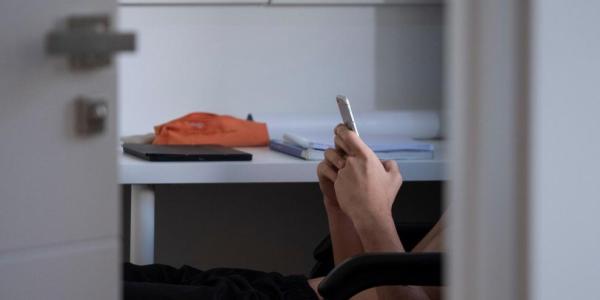 Adolescente mirando su teléfono móvil en la habitación