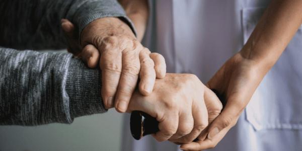 Manos de una persona dependiente con las manos de su cuidador principal