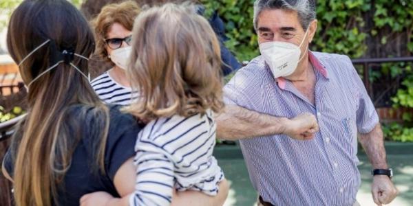 Familia saludándose con el codo en la calle durante la pandemia / EFE