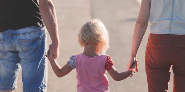 Un padre y una madre cogen de la mano a su hija