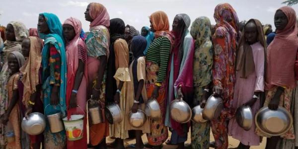 Mujeres sudanesas esperan para recibir arroz en Chad, tras huir de Sudán 