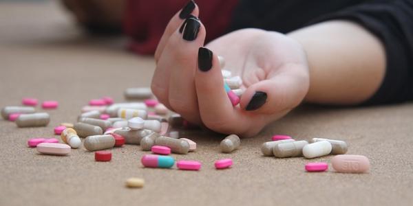 Mano de una chica protagonizando un intento de suicidio con pastillas